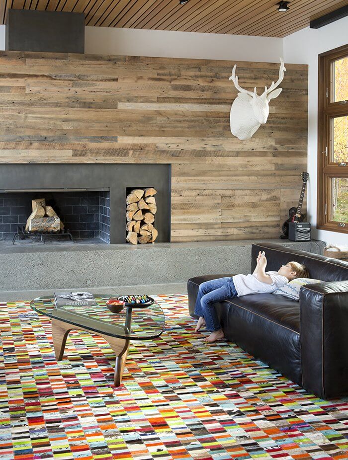 Como acertar na escolha do sofá de casa Sala de estar com mesa de centro noguchi, lareira contemporânea, parede revestida com madeira de demolição. No piso tapete colorido com pequenos retangulos.