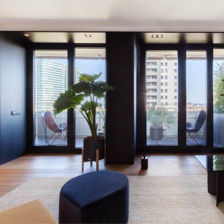 Reforma de Apartamento Moderno Llull por YLAB Arquitectos - Sala Integrada, parede azul, painel de madeira com portas do piso ao teto e Sacada