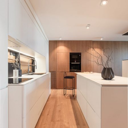 Reforma de Apartamento Llull por YLAB Arquitectos - Cozinha moderna com bancada em ilha branca, armários amadeirado.