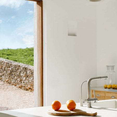 CasaE - Marina Senabre. Casa minimalista com cozinha com bancada em ilha, paredes brancas e caixilhos de madeira.