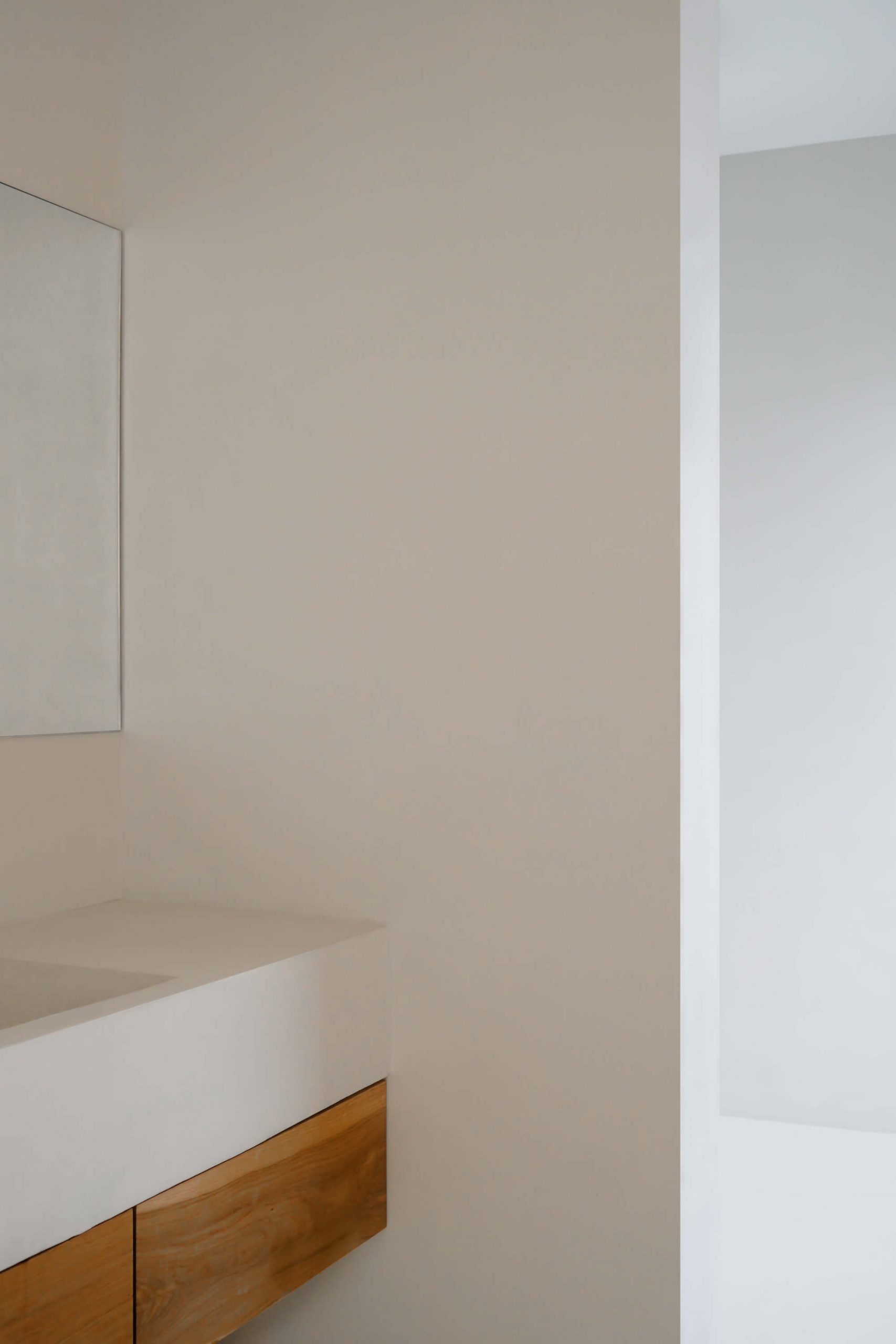 CasaE - Marina Senabre, banheiro minimalista com bancada branca e armários marrom.