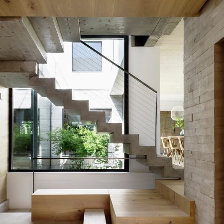 Casa Proyecto CH - Espanha. Escada de concreto aparente com alguns degraus em madeira. Parede de concreto aparente e janelas grandes.