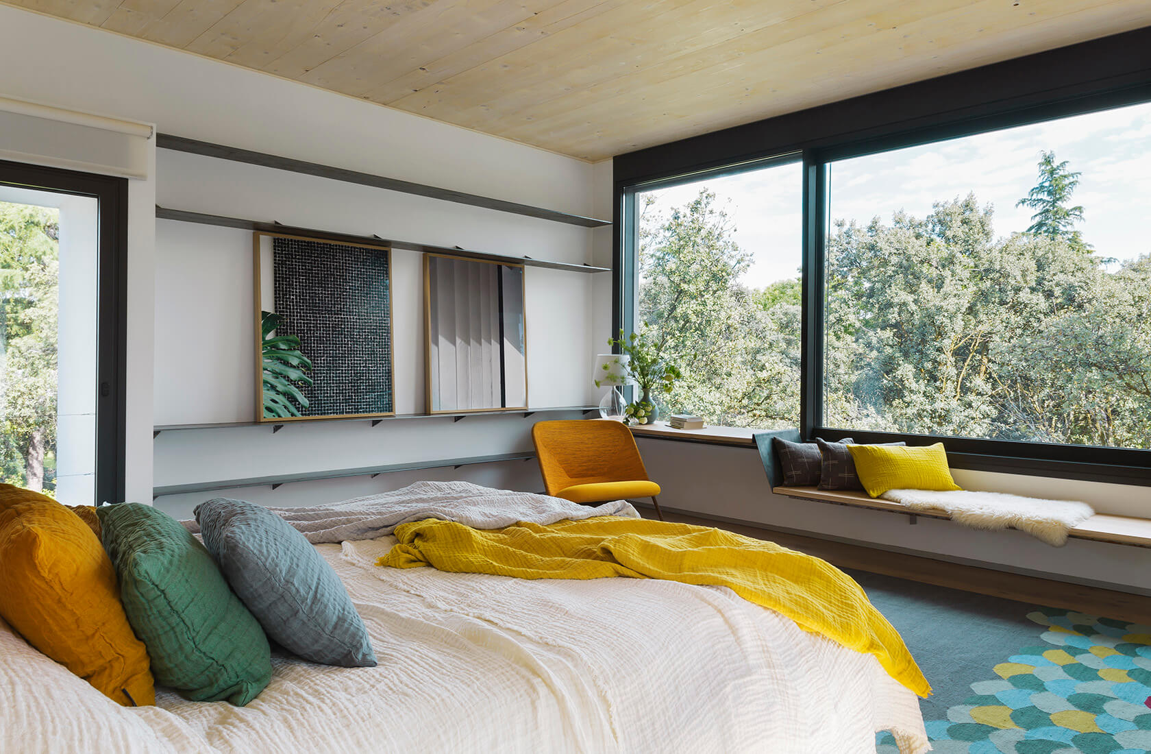Casa Proyecto CH - Espanha. Quarto com ambiente para relaxar com janelas grandes, poltrona amarela, quadros contemporâneos e piso de madeira.