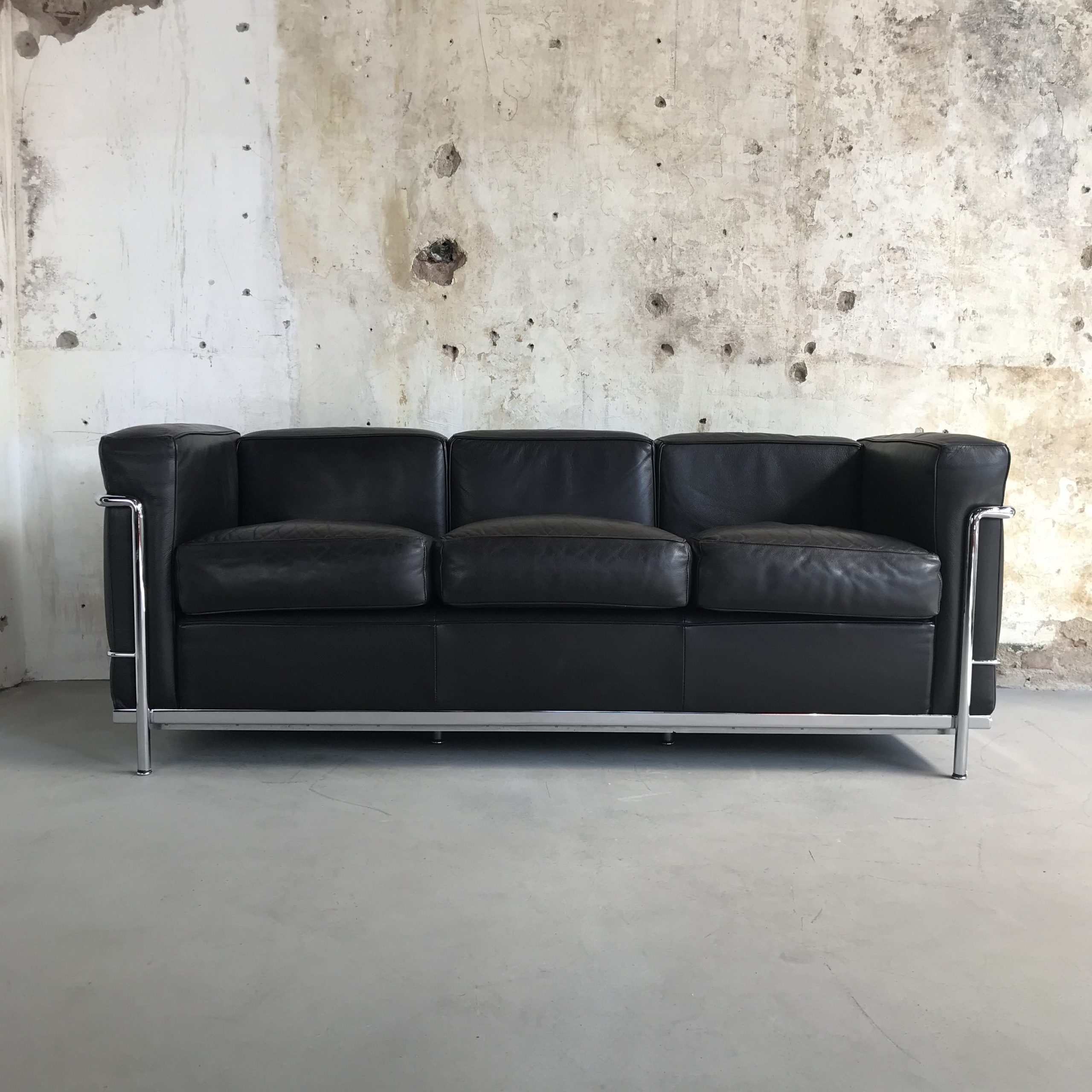 Sofa LC2 Masculino couro preto Ambientado parede concreto
